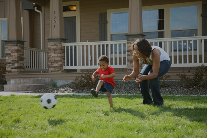 Family playing soccer outside of a new home. 