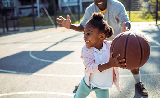 A father playing basketball with his daughter