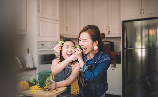 Mom and daughter playing with food in the kitchen
