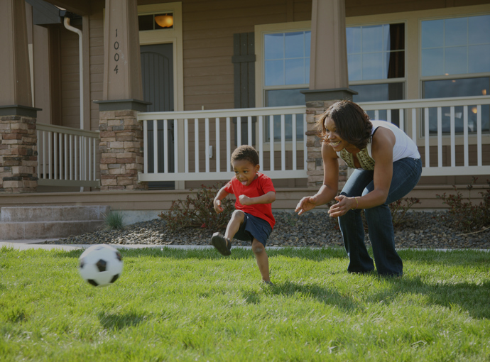 Family playing soccer outside of a new home. 