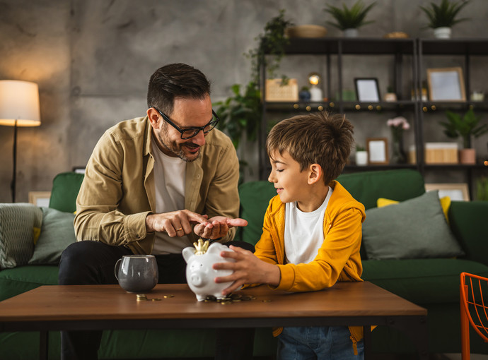 Father and child saving money in piggy bank