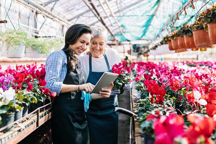 Two females looking at iPad in Greenhouse. 