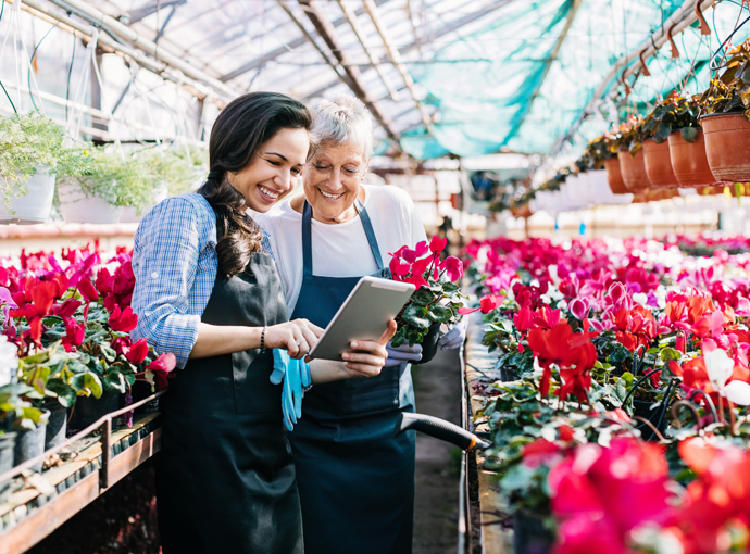 Two females looking at iPad in Greenhouse. 