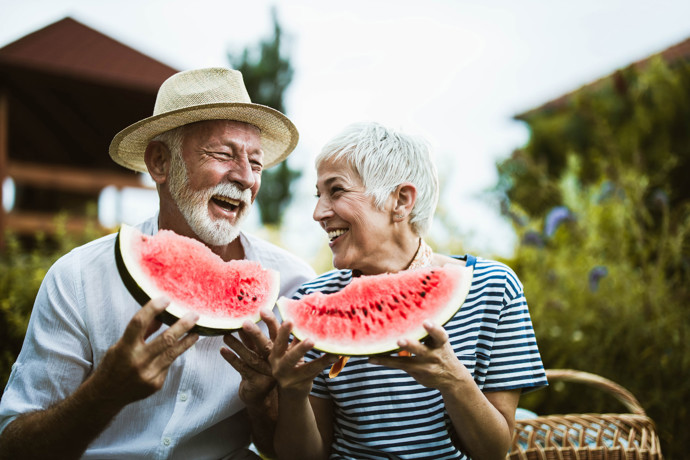 An older couple eating watermelon