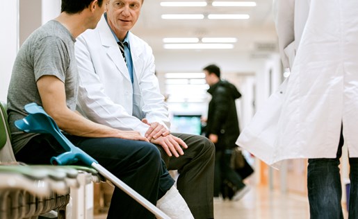 A man with crutches talking to his doctor in a hospital