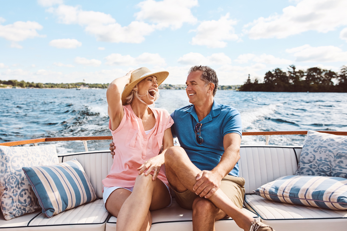 Couple laughing while enjoying time on their boat on a sunny day.