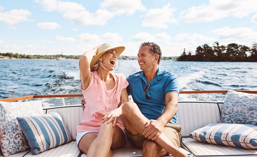 Couple laughing while enjoying time on their boat on a sunny day.