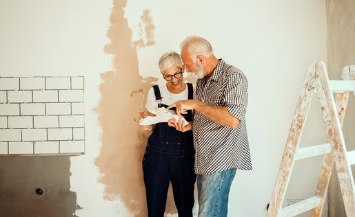 An older couple doing some painting in their house