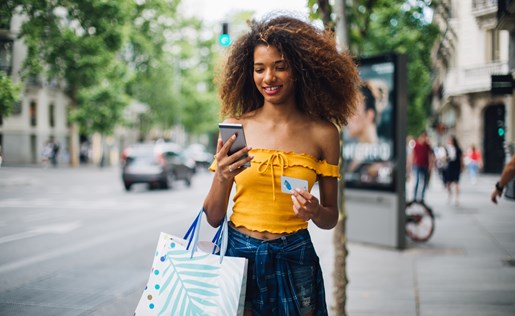 A woman with her phone and a bag of shopping items