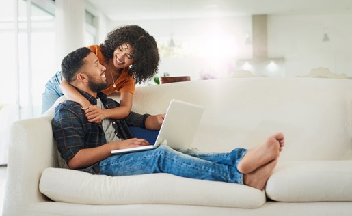 A couple lounging on the couch with a laptop