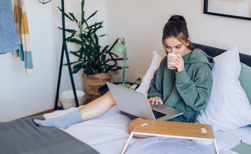 A college student in bed with her laptop