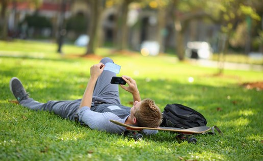 A student laying in the grass on a skate board