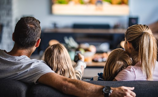 A family of four enjoying a movie at home on their television