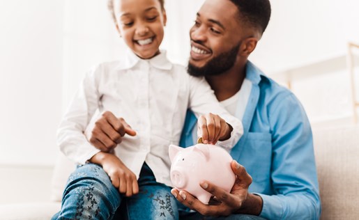 A father and daughter saving money in a piggy bank