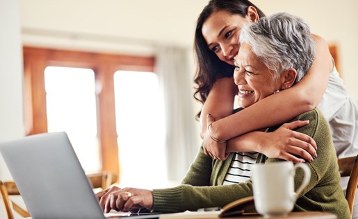 A woman hugging her mom in front of a laptop