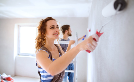 A woman roller painting a wall