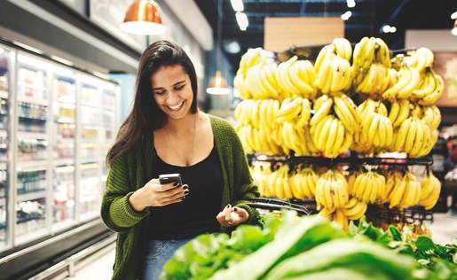 Woman in the produce department looking at her phone.