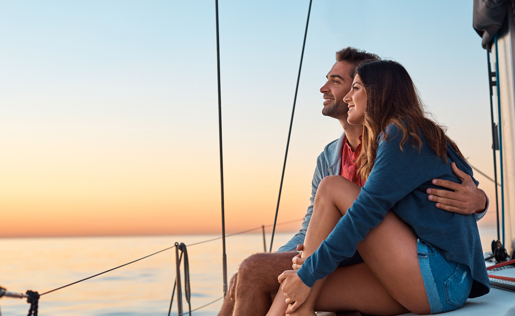 Couple hugging, watching a sunset on their sailboat.