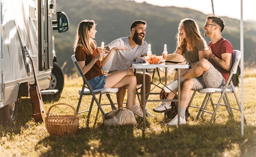 Four friends eating outside their RV