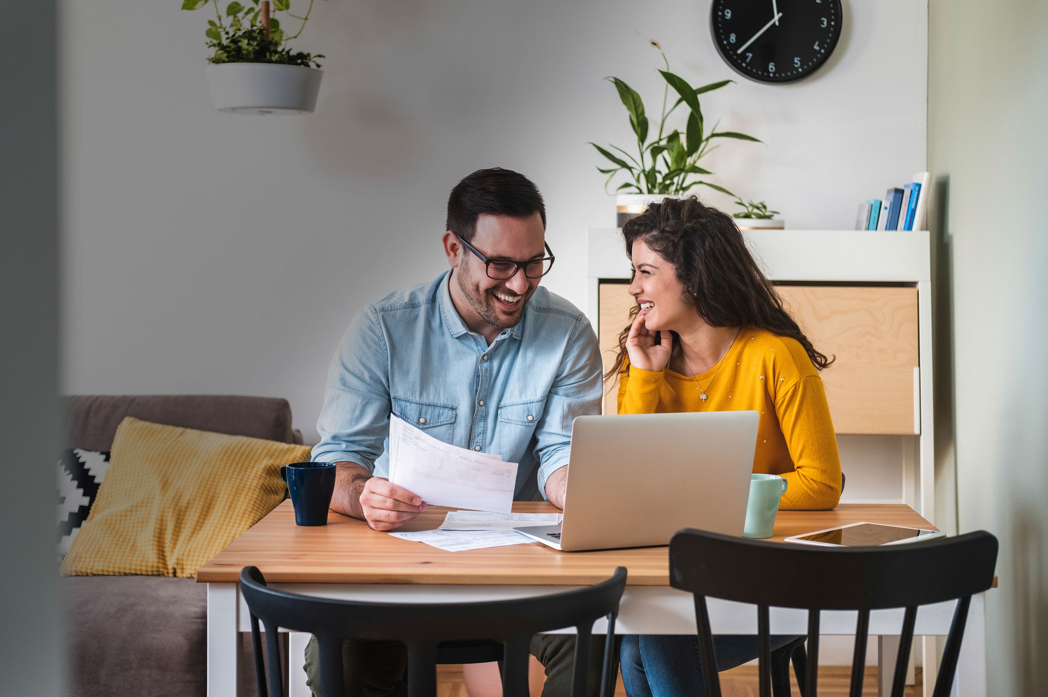 A couple paying bills at the dining room table